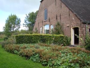 een bakstenen huis met een tuin ervoor bij Bed & Breakfast de Neust in Beesd