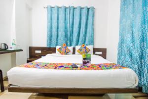 a bedroom with a large bed with blue curtains at FabHotel Pruthamesh Pride in Nashik