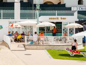 a group of people sitting at a snack bar with umbrellas at Tropical Sol in Albufeira