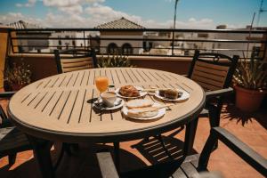 una mesa de madera con comida y bebida en el balcón en Hotel Nuro en Barbate