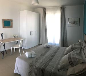 a bedroom with a bed and a table and a window at Appartamento Gambero Beach in Santa Teresa di Riva