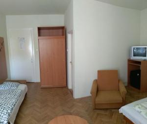 a room with a bed and a chair and a television at Siófokroom24 in Siófok