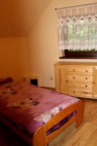 a bedroom with a bed and a dresser and a window at Zawoja Chaty Górskie D5 in Zawoja