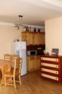 a kitchen with a table and a white refrigerator at Zawoja Chaty Górskie D5 in Zawoja