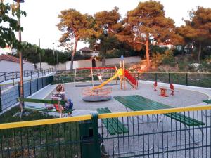 a woman sitting on a bench in a playground at Apartments Doulos in Splitska