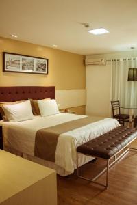 ein Hotelzimmer mit einem Bett und einer Bank in der Unterkunft Caruaru Park Hotel in Caruaru