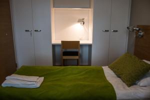 a bedroom with a bed with a green blanket and a chair at Vierumäki Chalets 4414 in Vierumäki