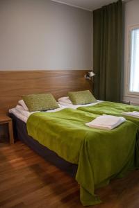 a bedroom with two beds with green sheets and a window at Vierumäki Chalets 4414 in Vierumäki