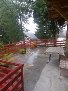 a patio with a picnic table and a fence at vila strugurelu hostel in Predeal