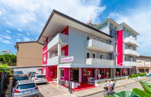 un edificio colorido con coches estacionados frente a él en Hotel Romantik en Lignano Sabbiadoro