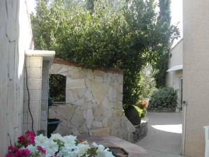 a stone wall with flowers in front of a house at les alicantes in Coursan