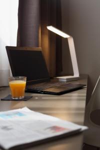 un bicchiere di succo d'arancia seduto su una scrivania con computer portatile di City Hotel & Suites a Foligno
