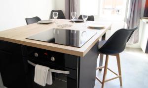 uma cozinha com uma ilha com um lavatório e cadeiras em Appart Hôtel Lille PAO em Lille