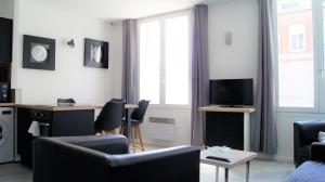 リールにあるAppart Hôtel Lille PAOのリビングルーム(椅子、テーブル、テレビ付)