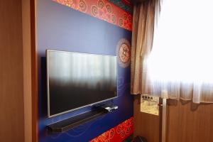 TV de pantalla plana colgada en una pared azul en Monalisa Hotel en Tainan