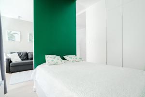 ポズナンにあるLux Apart Przemysłowaの緑の壁のベッドルーム1室(白いベッド1台付)