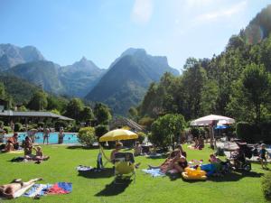 a group of people sitting in the grass by a pool at Apartments Landhaus Sonnheim in Lofer