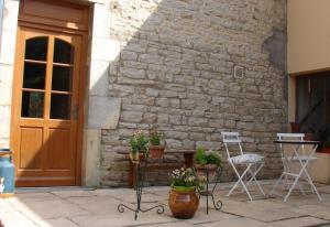 Myon的住宿－Maison Les greniers，庭院配有两把椅子和一张桌子,还有一些植物