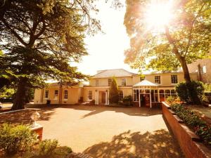 a large house with the sun shining behind it at Gainsborough House Hotel in Kidderminster