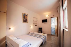 a small bedroom with a bed and a cross on the wall at Mrkonjic Branko & Marija Apartmani in Omiš