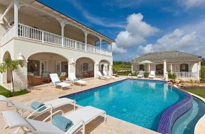 a villa with a swimming pool and a house at Howzat! by Island Villas in Saint James