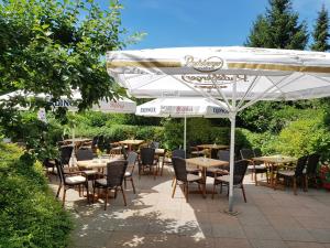 eine Terrasse mit Tischen und Stühlen unter einem Sonnenschirm in der Unterkunft Ringhotel Klövensteen in Schenefeld