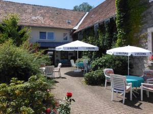 un patio con mesas, sillas y sombrillas en Ferienwohnungen Westfalenhof, en Willingen