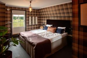 a bedroom with a bed with pillows and a window at Tweed Hotell Skaftö in Fiskebäckskil