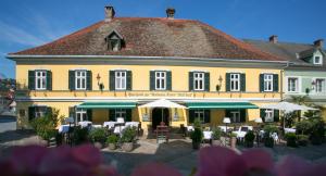 un bâtiment jaune avec des tables et des parasols devant lui dans l'établissement Stadthotel zur goldenen Krone, à Weiz