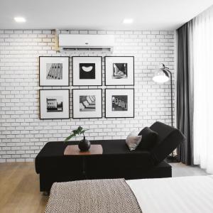 a living room with a black couch and a brick wall at Zivi Nimman in Chiang Mai