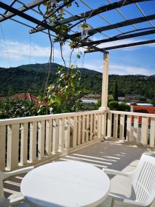 un patio con tavolo e sedie bianchi sul balcone. di Apartments and Rooms Villa Mir a Zaton