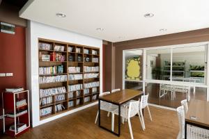 a library with a table and chairs and bookshelves at ONPA Hotel & Residence Bangsaen in Bangsaen