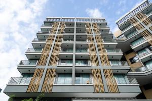 a tall building with gold doors and windows at ONPA Hotel & Residence Bangsaen in Bangsaen