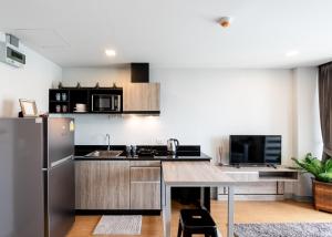 a kitchen with a stainless steel refrigerator and a table at ONPA Hotel & Residence Bangsaen in Bangsaen