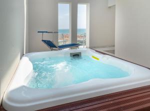 a bath tub with a chair in a room at Hotel Ambassador in Rimini