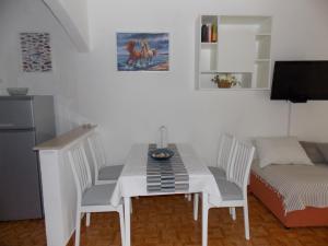 a white dining room table with chairs and a couch at Rocco apartments in Pag