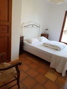 een slaapkamer met een wit bed en een stoel bij Maison les Salles-sur-Verdon in Les Salles-sur-Verdon