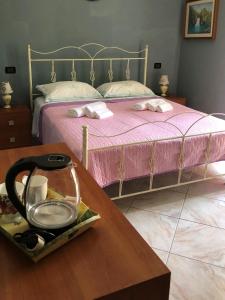 una camera da letto con un letto con lenzuola rosa e un tavolo in legno di La Maison Fleurie a San Nicola Arcella