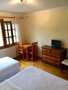 - une chambre avec 2 lits, une table et un bureau dans l'établissement Posada Adela, à Santillana del Mar