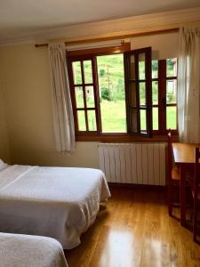 a bedroom with two beds and a table and windows at Posada Adela in Santillana del Mar