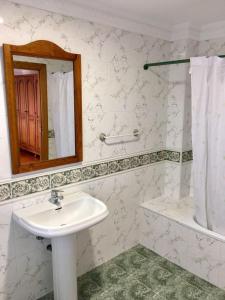 uma casa de banho com um lavatório, um espelho e um chuveiro em Posada Adela em Santillana del Mar