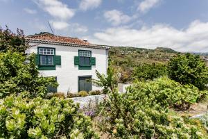 a white house with green shutters in a garden at El Molino in Villa de Mazo