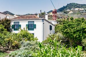 a white house with green shutters and a windmill at El Molino in Villa de Mazo