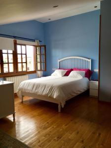 a blue bedroom with a white bed with red pillows at Posada Adela in Santillana del Mar