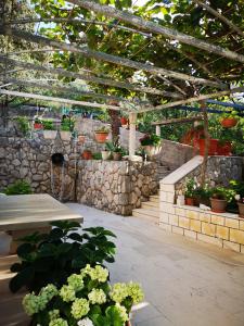 a patio with potted plants and a wooden pergola at Apartments and Rooms Villa Mir in Zaton