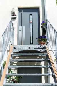 a staircase leading to a blue door with flowers at Ferienwohnung Mittendrin in Bergisch Gladbach