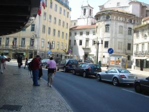 a group of people walking down a street with cars at Baixainn in Lisbon