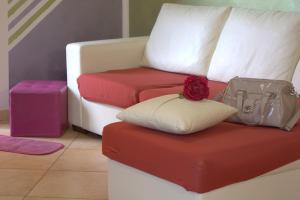 Un sofá con dos cojines y una flor roja. en Casa al mare, en Tusa