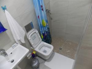 Un baño con inodoro, lavabo y ducha. en Elvin Apartments, en Sarandë
