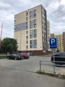 un parcheggio con auto parcheggiate di fronte a un edificio di Mantas apartments a Šiauliai